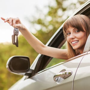 Caucasian car driver woman smiling showing new car keys and car.