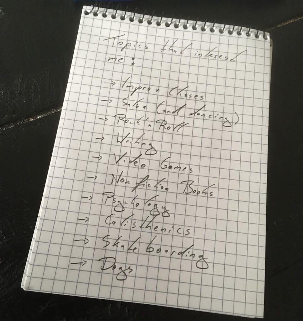 list of interests for friend cirlce written on a note pad. interests include improv, salsa dancing, rock n' roll, writing, video games, psychology, and calisthenics.