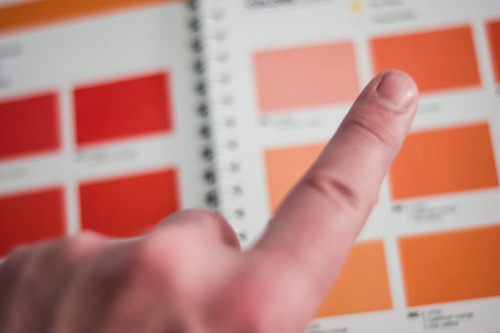 person's finger choosing a color from a book of color options