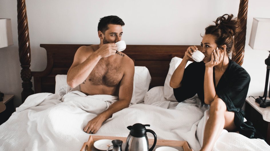 Man and woman enjoying morning coffee in bed