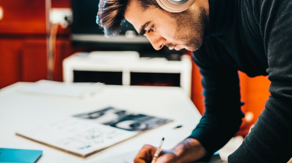 A man with headphones on drawing