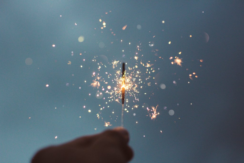 A hand holding a single burning sparkler