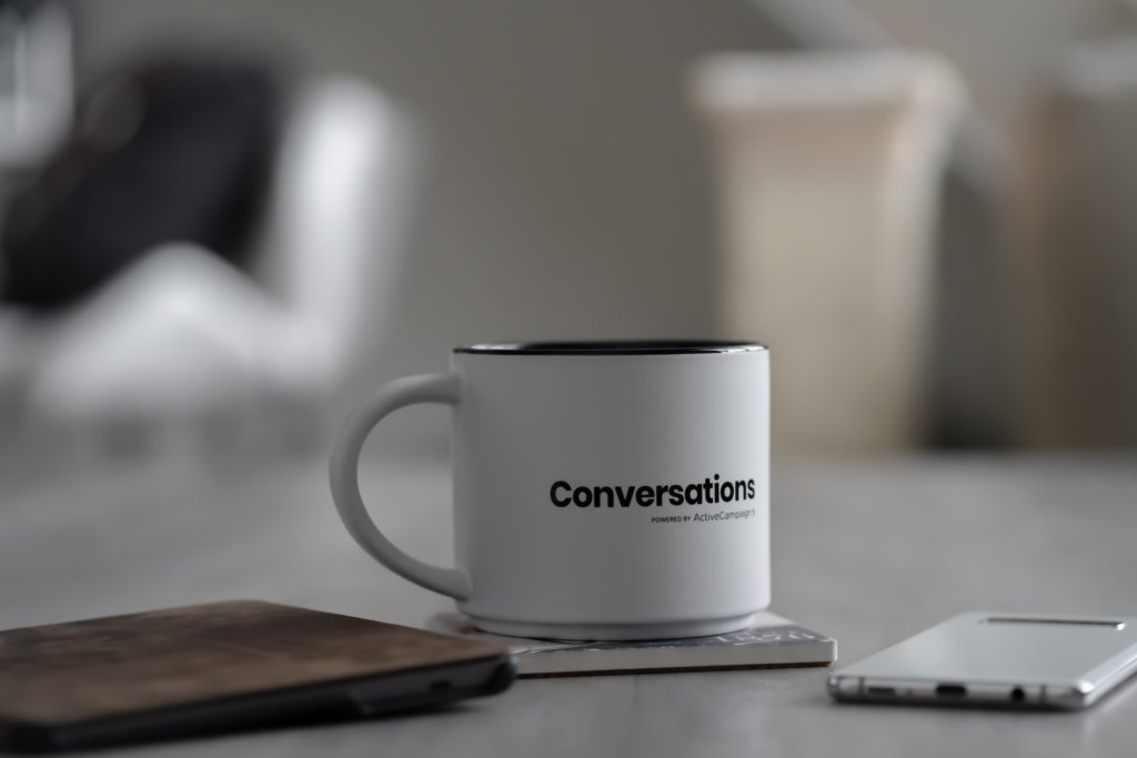 A white coffee mug with the word Conversations printed on it