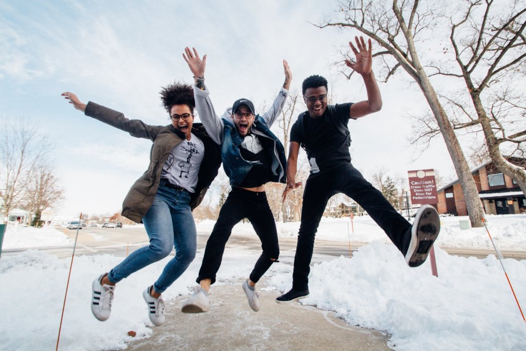 Three humans jumping in the air and looking happy