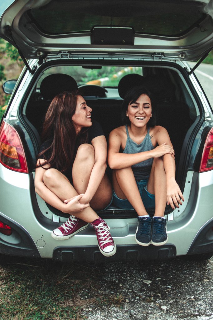 Two girls laughing in the back of a car