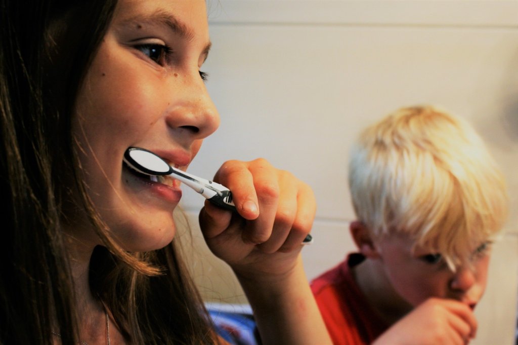 A close up of two kids brushing their teeth