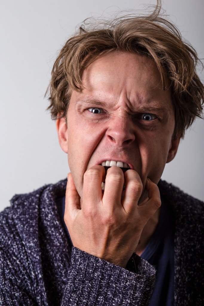 A men so stressed out he's putting his hand in his mouth angrily