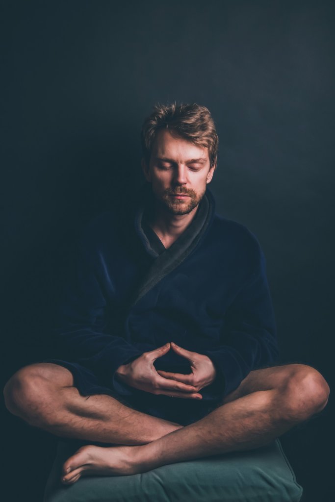 Man meditating in dark blue bath robe