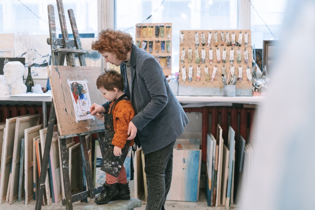 Woman teaching a little boy how to paint