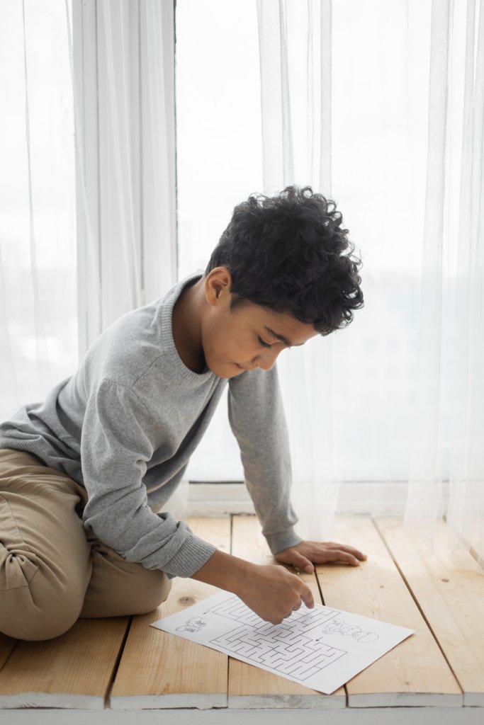 Little boy tracing a maze on a piece of paper