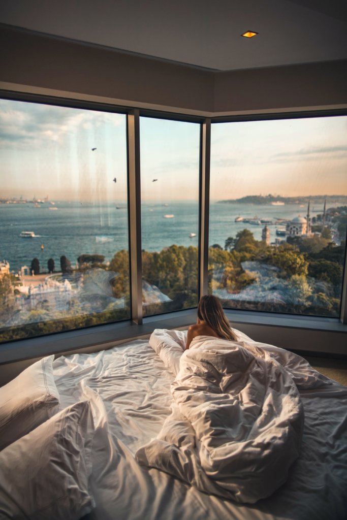 A woman lying in bed looking out over a beautiful ocean view