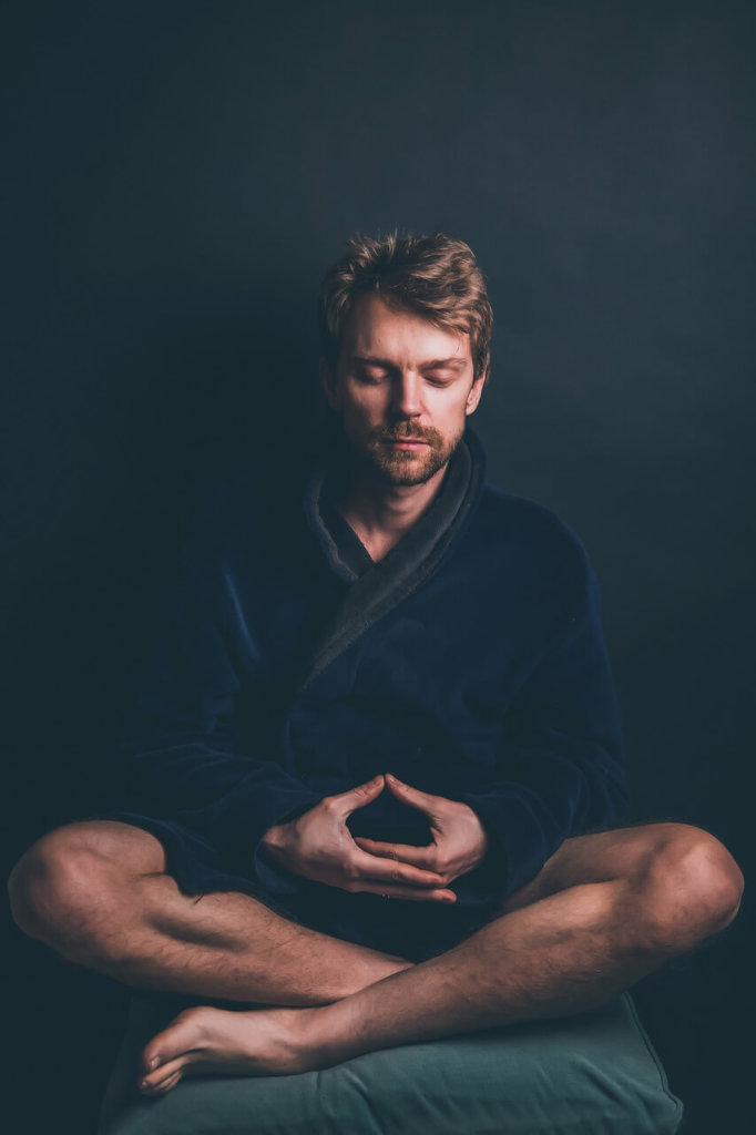 Man meditating in cross legged pose wearing blue robe