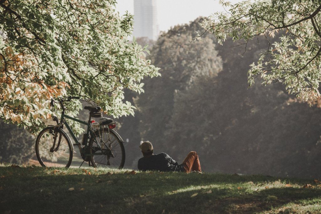 A man resting in a park next to his bicycle