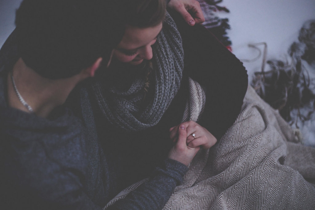 A couple sitting next to one another holding hands